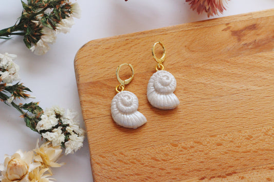 Pearly shell shaped earrings on a wooden board