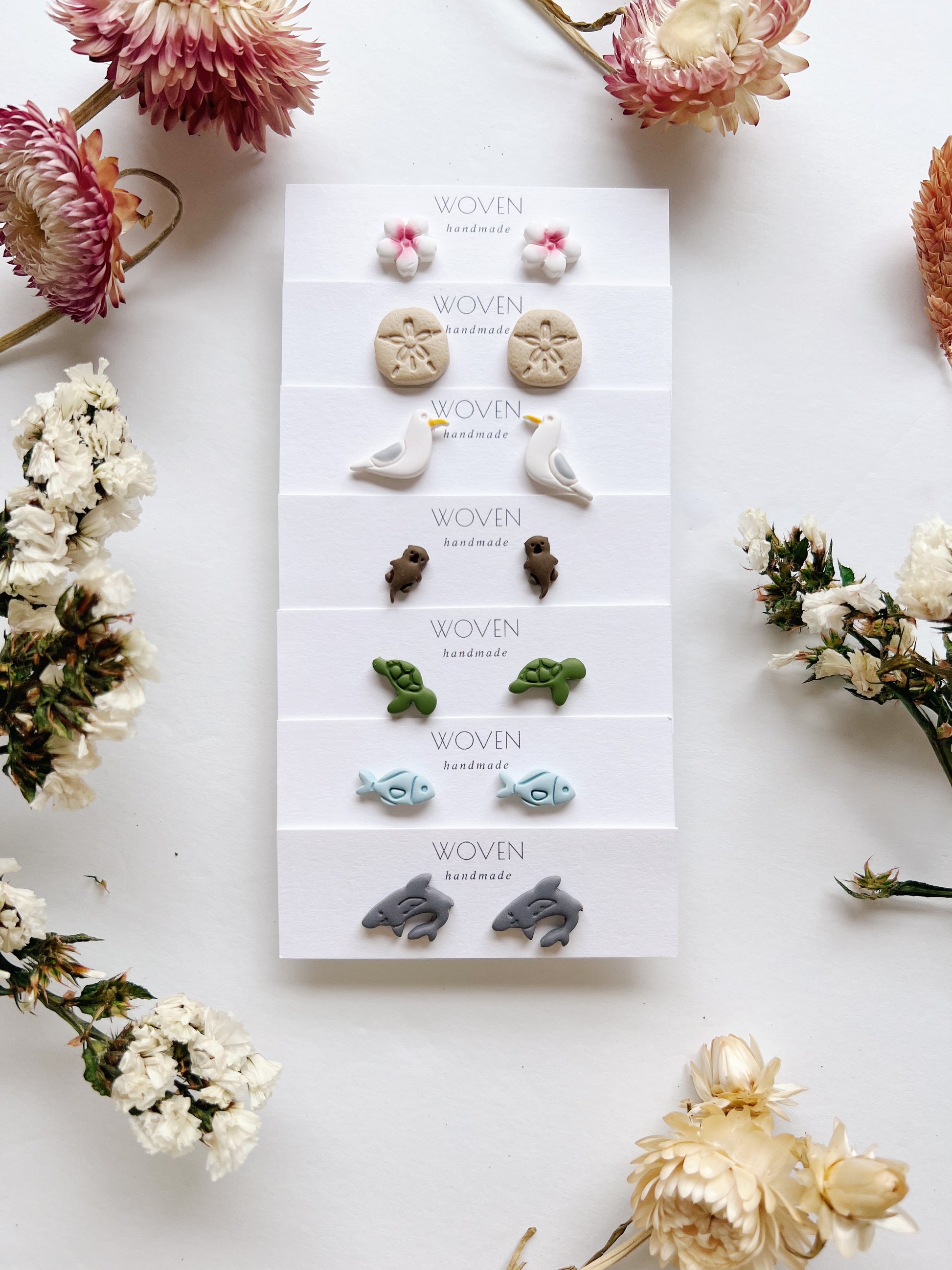 Set of earrings on a 'Woven' branded card with flowers around