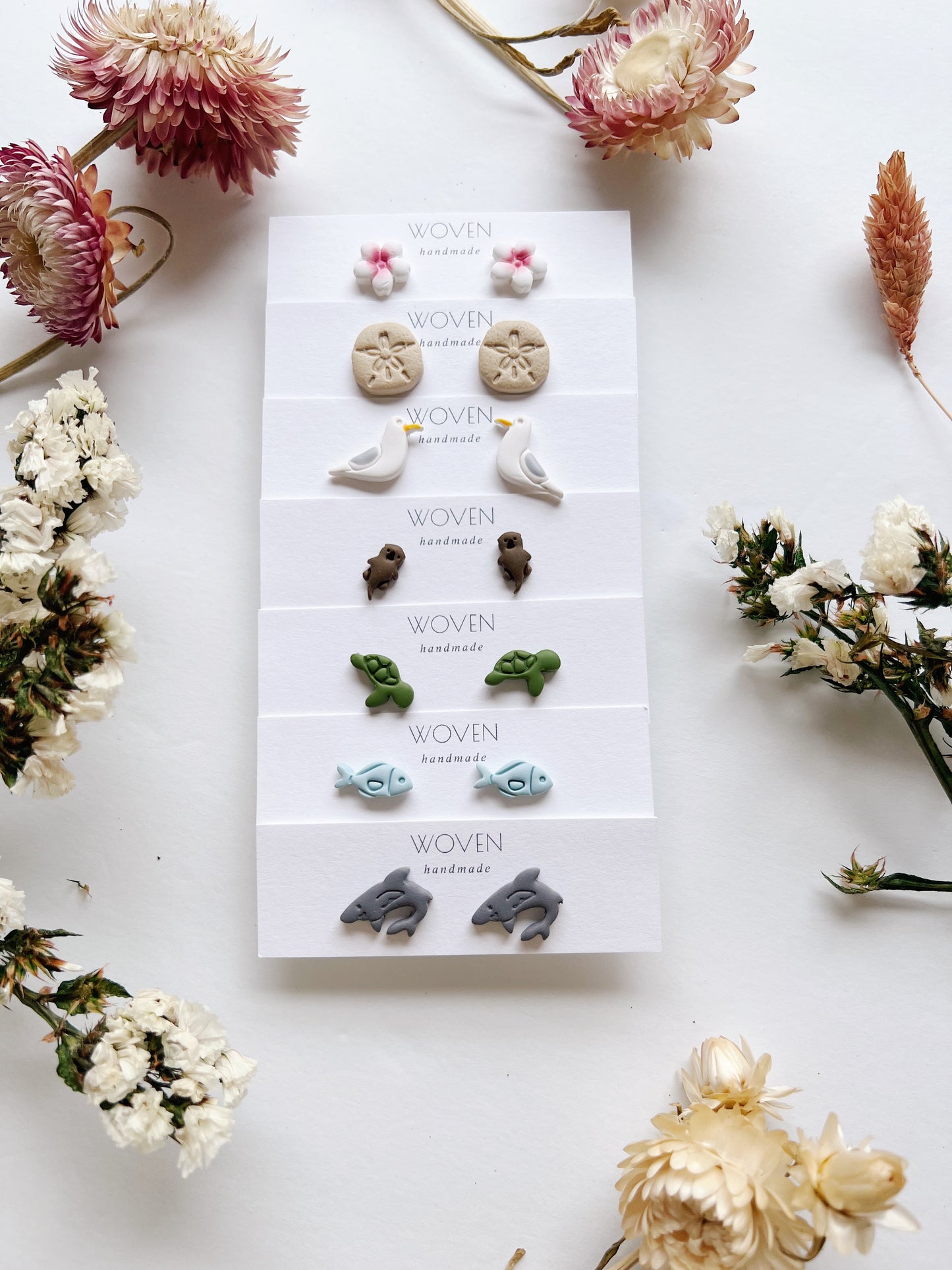 Set of earrings on a display card with dried flowers around
