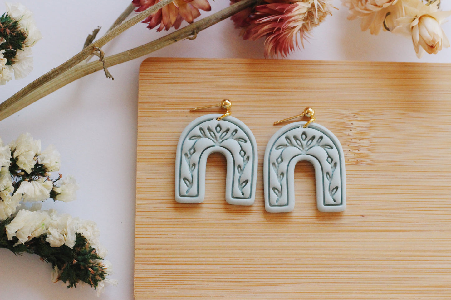 Light green arch earrings with a vine imprint