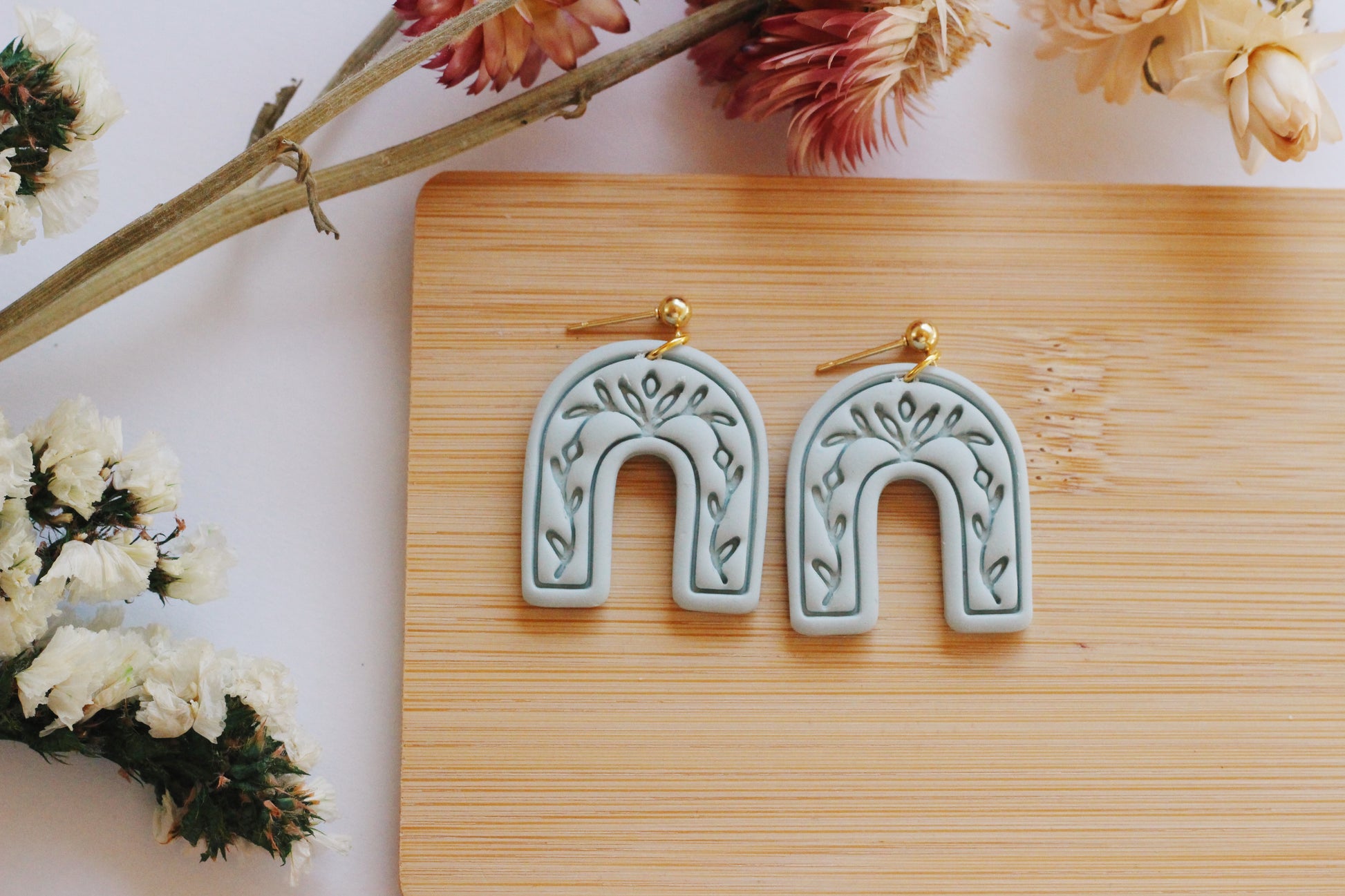 Light green arch earrings with a vine imprint