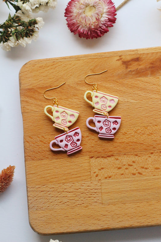Teacup earrings on a wooden board with flowers in the background