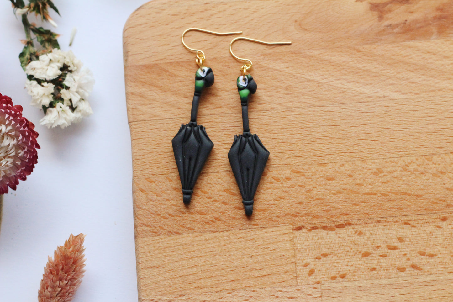 Black earrings on a wooden surface with flowers in the background