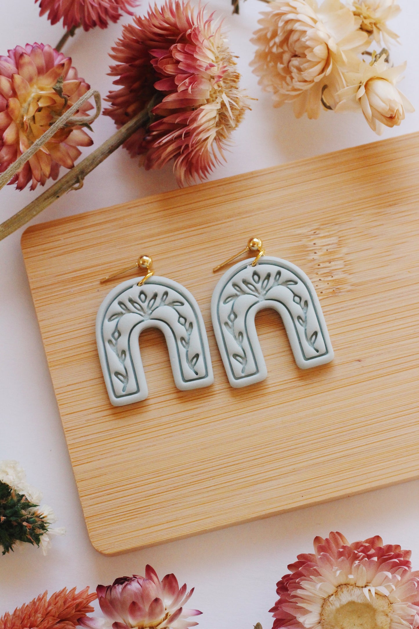 Light green arch earrings with a vine imprint