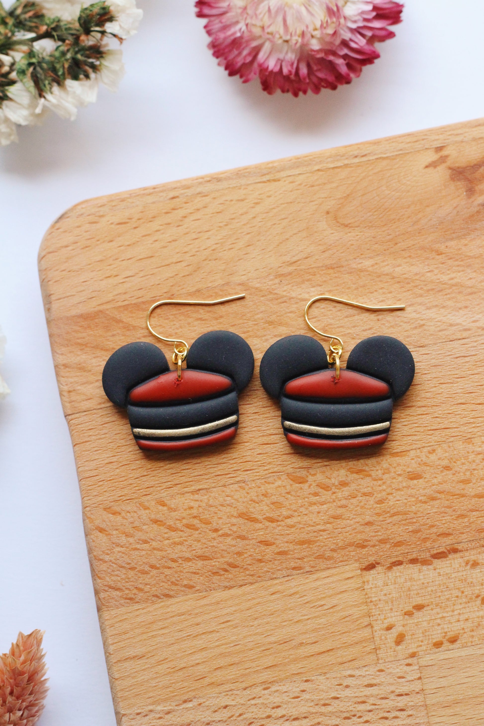 Mouse ears earrings on a wooden board with flowers in the background