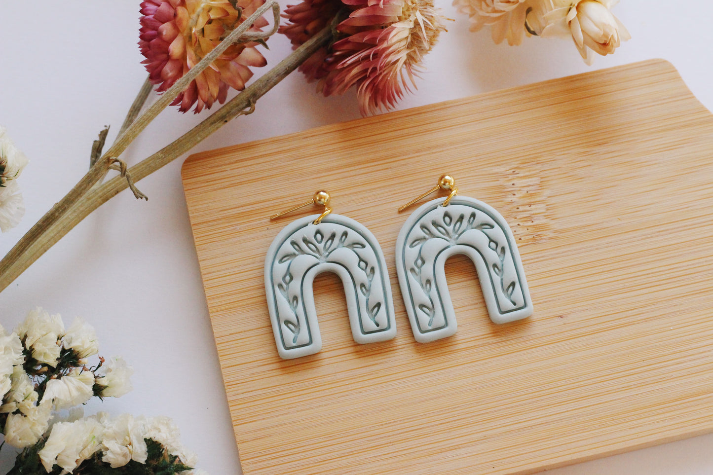 Light green arch earrings with a vine imprint