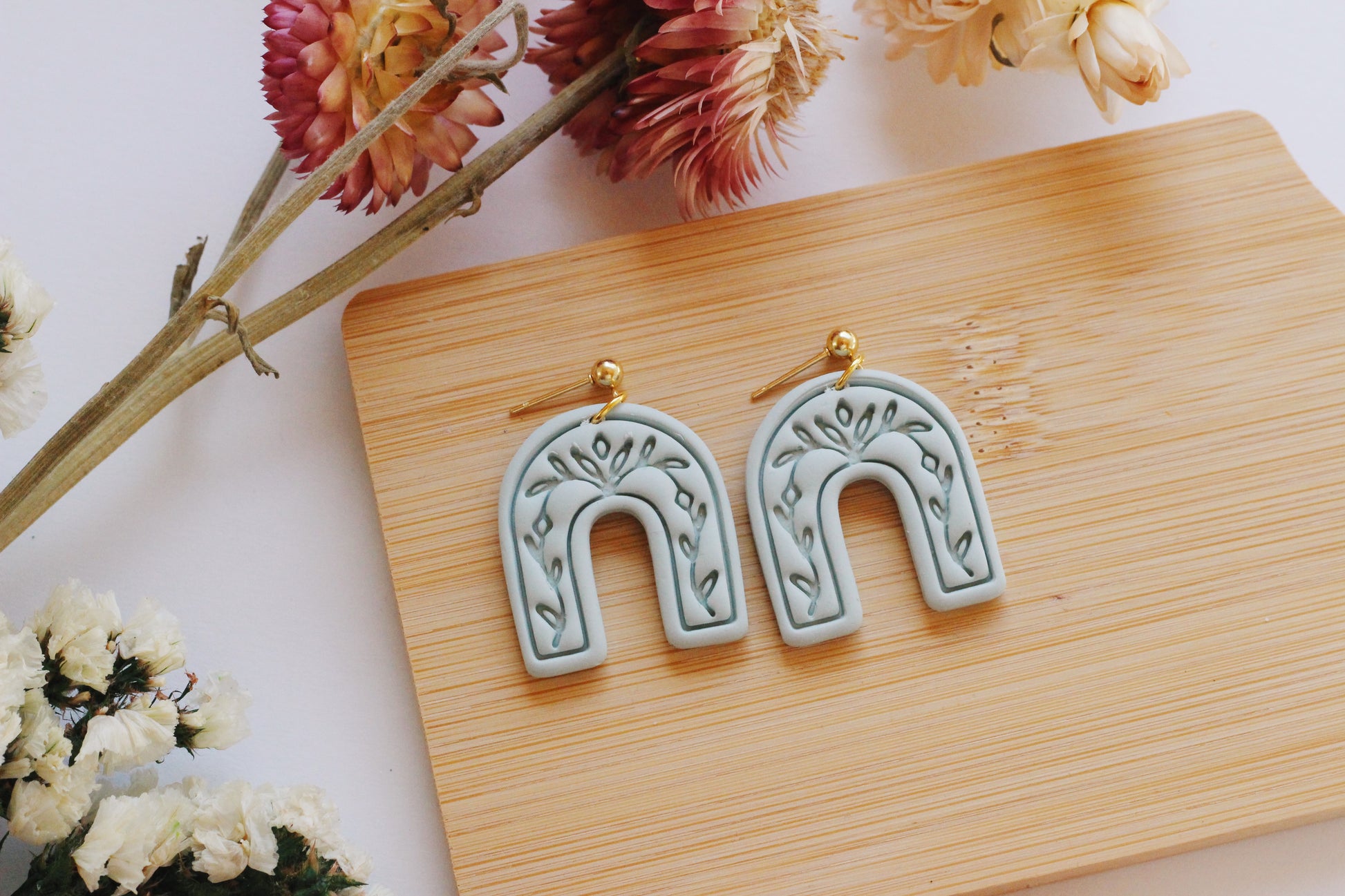 Light green arch earrings with a vine imprint