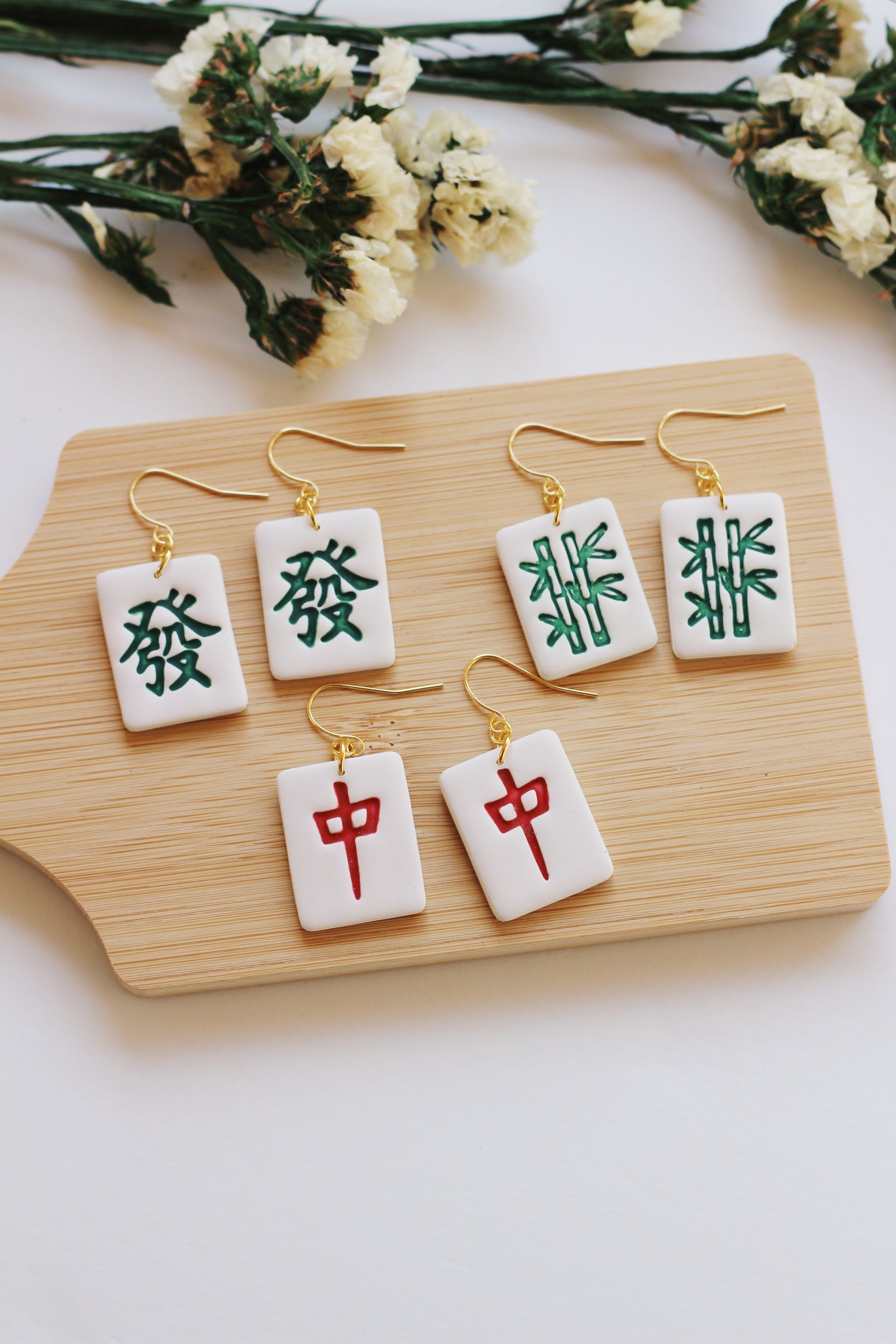 Set of earrings with Chinese characters on a wooden board with flowers in the background