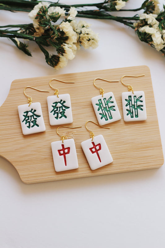 Set of earrings with Chinese characters on a wooden board with flowers in the background