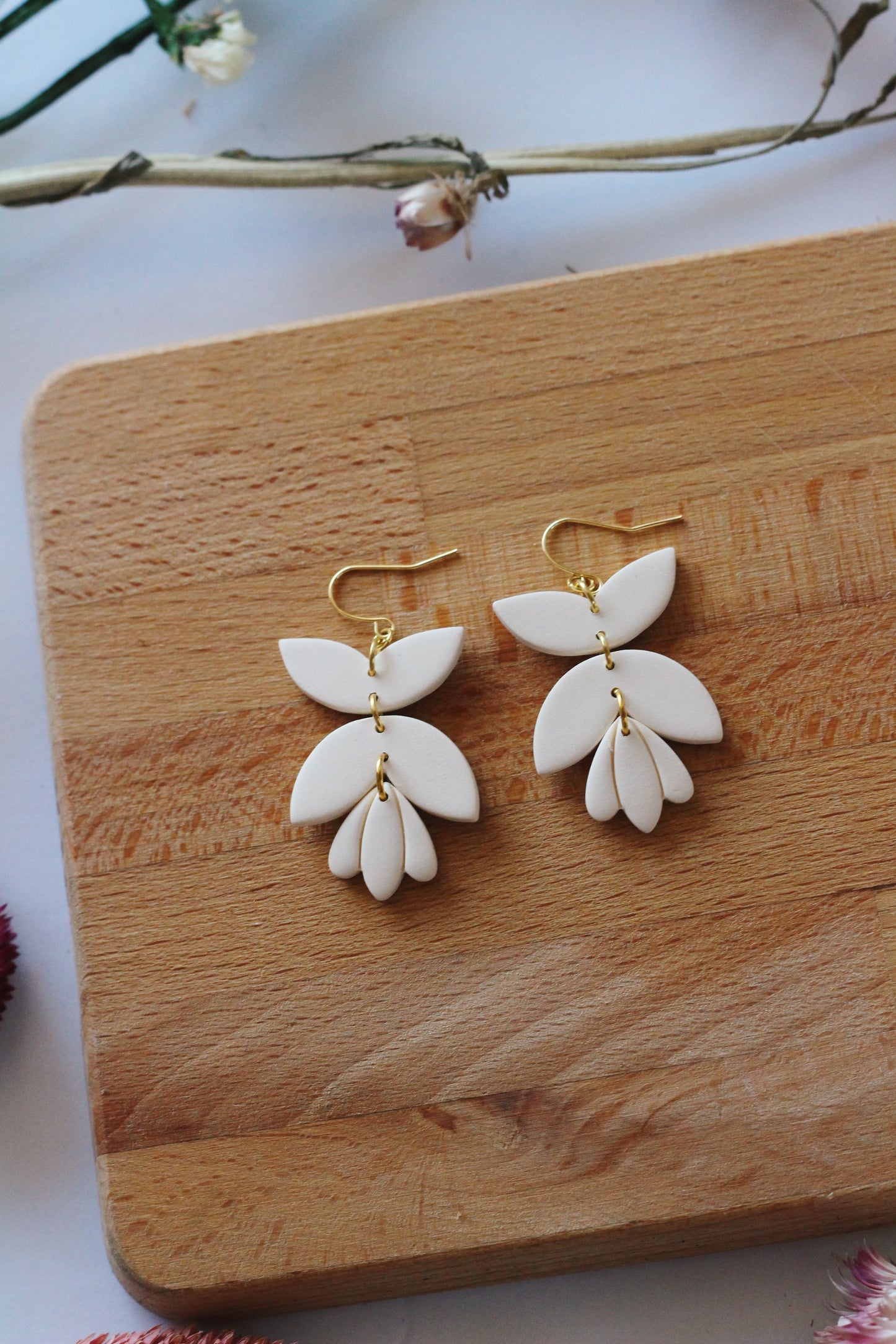 White floral earrings on a wooden board with a light background