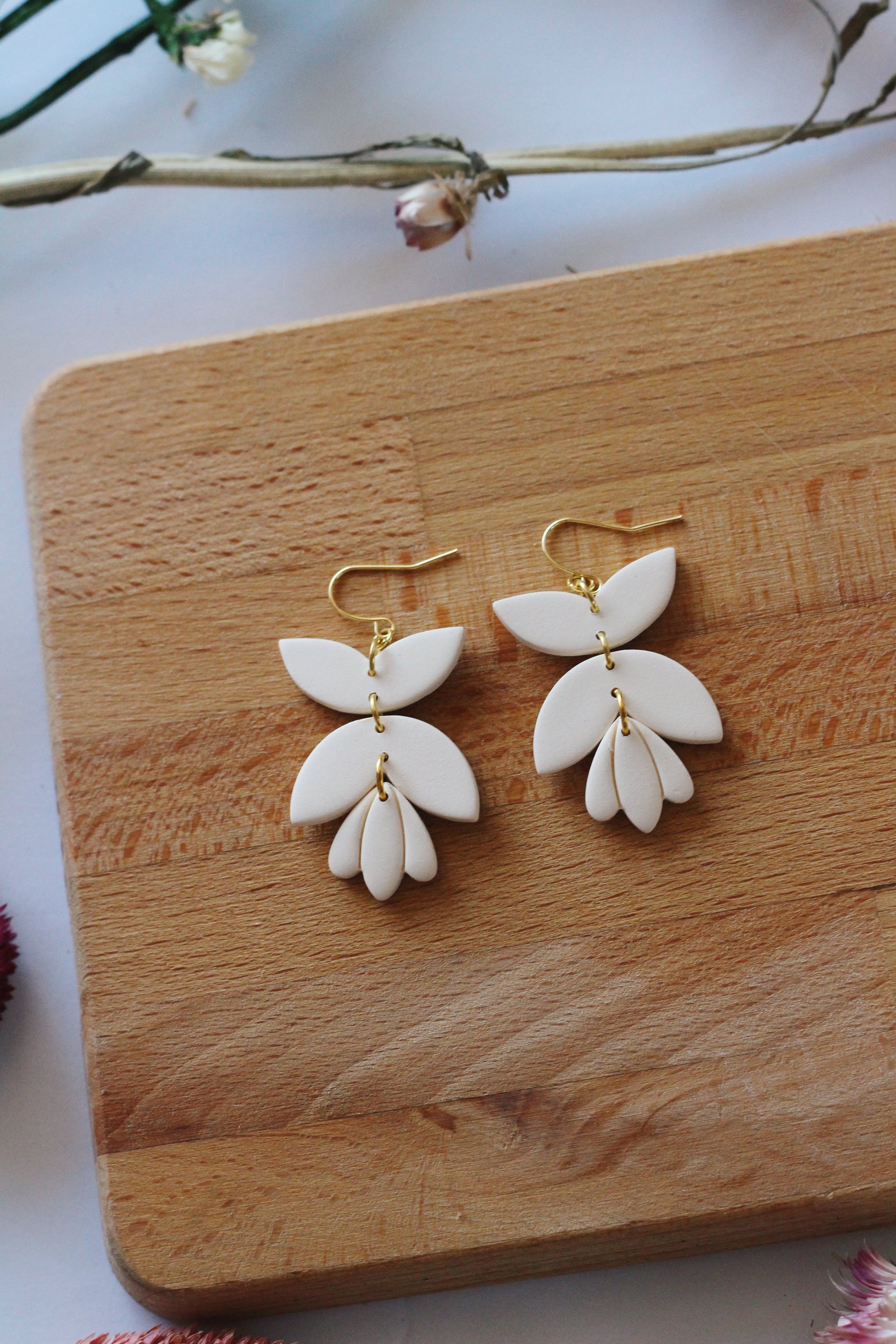 White floral earrings on a wooden board with a light background