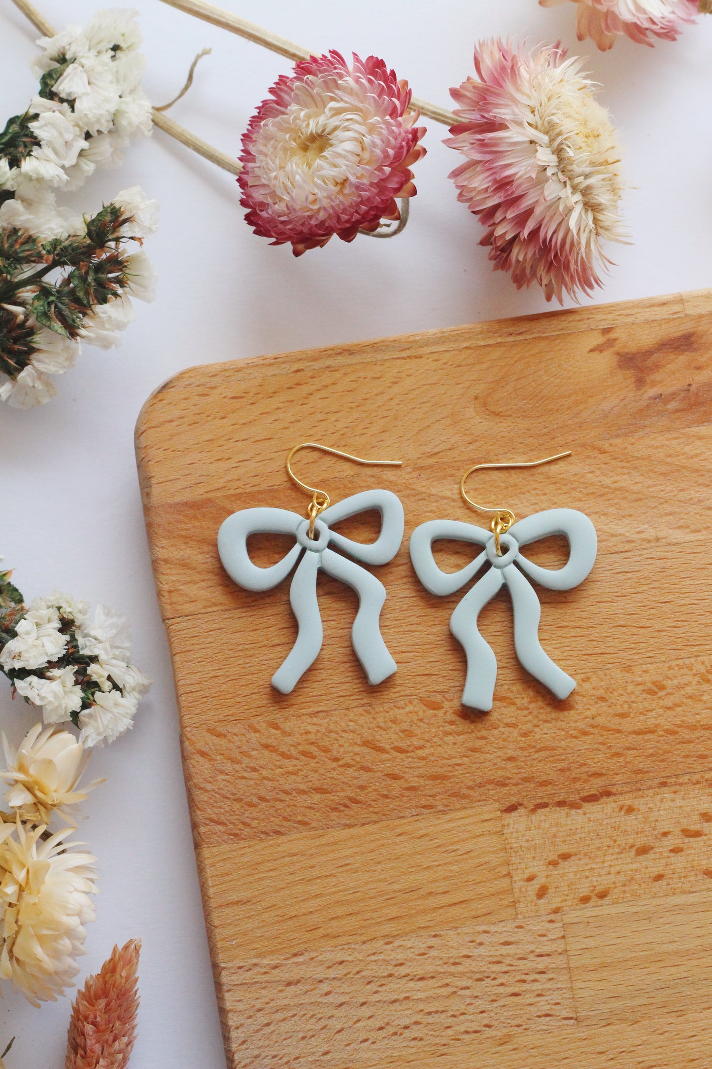 Light blue bow earrings on wooden background