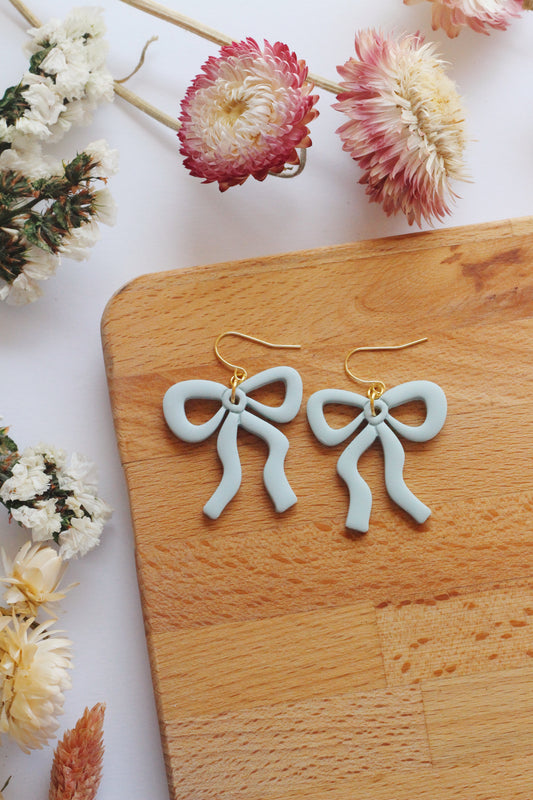 Light blue bow earrings on wooden background