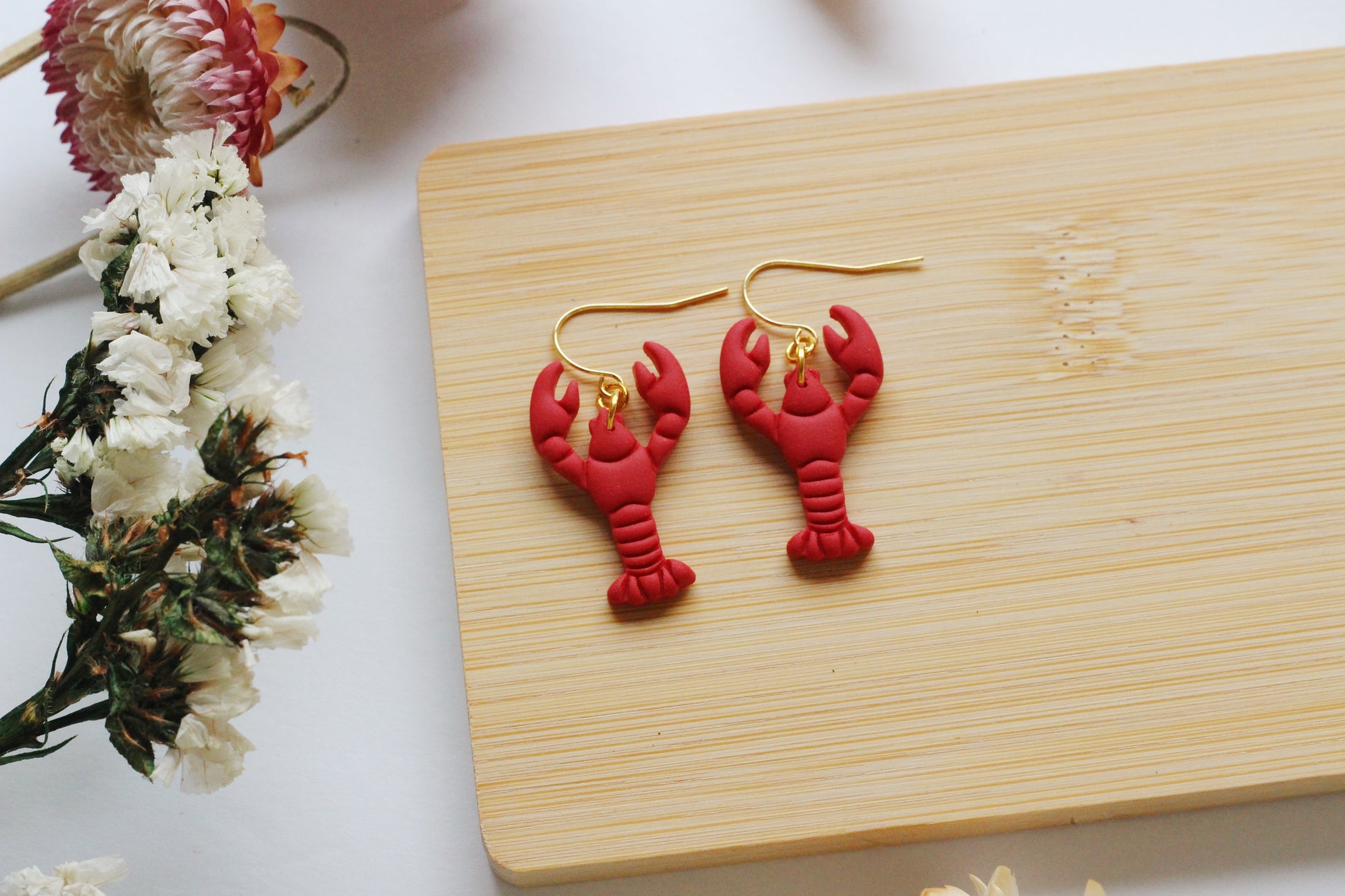 Red lobster earrings on wooden board